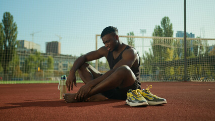 African American footballer sportsman sit on field suffer pain sharp ache muscle cramp foot injury...