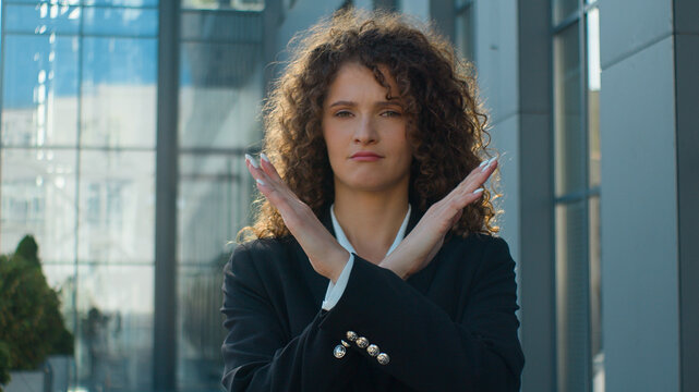 Caucasian serious confident woman business girl female businesswoman showing stop gesture at camera crossed hands never no not sign crossing arms negative attitude forbid reject deny in city outdoors