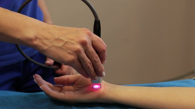 Hand low level laser therapy to promote healing of soft tissues 4k video. Infrared treatment of hand to manage pain, numbness and tingling. Laser therapy to improve blood flow and immune system.