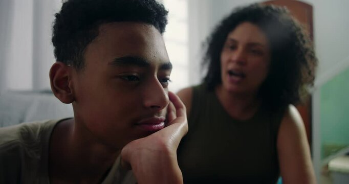Teenager resting hands against face in deep thought, subtly ignoring mother&rsquo;s efforts to engage, capturing emotional complexity in strained family dynamics