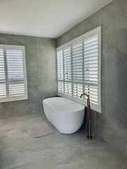 A serene bathtub by a window in a grey tiled bathroom