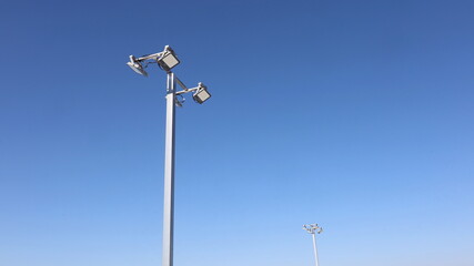 Lamp on metal pole. Pair of square LED lights on modern parking lot on steel pole in bottom view on bright blue sky background. Selective focus
