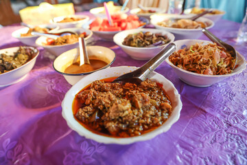 Various Burmese curries are placed on the table, pork curry, meat dish vegetables, and other curries.