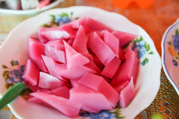 Close-up of pink coconut jelly served on a plate, Burmese style.