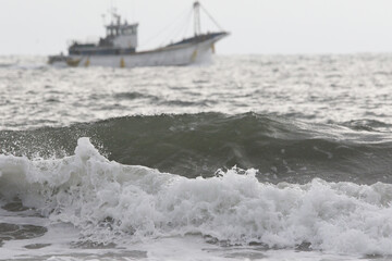波しぶきと漁船