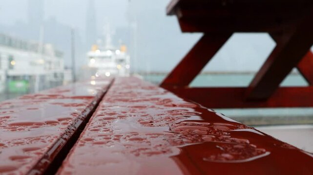 A rainy harbor is visible, with raindrops dripping down onto picnic tables by the sea.비가내리는 항구가 보이고 바닷가 피크닉테이블엔빗물이 떨어집니다.