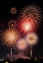 Multiple firework bursts in the night sky above city buildings