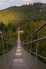 Obraz premium Bottom view of a modern pedestrian suspension bridge connecting castles on the mountain peaks of the Alps near Innsbruck. highline179
