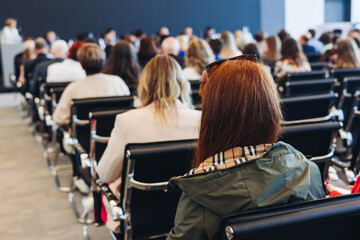 Audience at the modern conference hall listens to panel discussion, people on a congress event together listen to speaker on stage at convention, business seminar, large venue for forum presentation