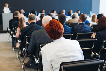Audience at the modern conference hall listens to panel discussion, people on a congress event...