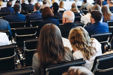 Audience at the modern conference hall listens to panel discussion, people on a congress event...
