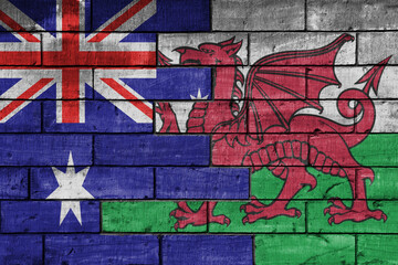 Obraz premium colourful painted big flag of australia and flag of wales on a massive old brick wall background. concept