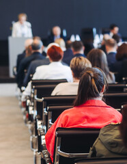 Audience at the modern conference hall listens to panel discussion, people on a congress event...