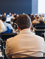 Audience at the modern conference hall listens to panel discussion, people on a congress event together listen to speaker on stage at convention, business seminar, large venue for forum presentation