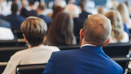 Audience at the modern conference hall listens to panel discussion, people on a congress event together listen to speaker on stage at convention, business seminar, large venue for forum presentation