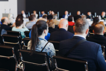 Audience at the modern conference hall listens to panel discussion, people on a congress event together listen to speaker on stage at convention, business seminar, large venue for forum presentation