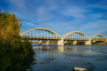 Naklejka premium A bridge spans a river with a blue sky in the background