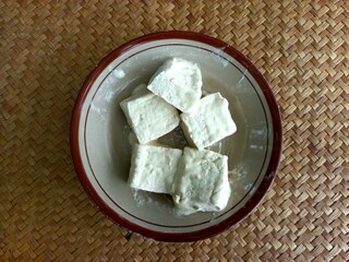 Tofu coated in batter placed on a plate, ready to be fried