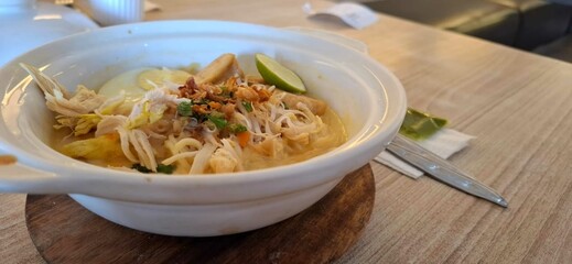 Mie Celor, noodle soup with pork in white bowl on wooden table