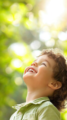 Fototapeta premium Joyful child looking up in sunny green environment
