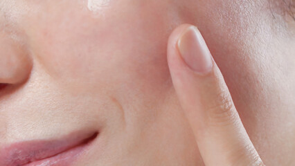 人差し指で頬の部分に触れている人物の顔のクローズアップ