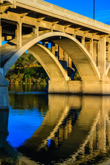 A bridge spans a river with a reflection of the bridge in the water