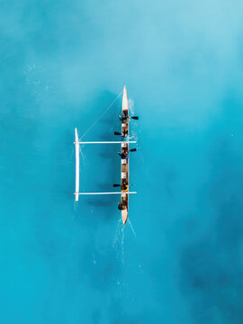 Drone Aerial View of a Canoe Gliding Through Waves in Hawaii's Transparent Blue Ocean