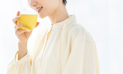 グラスに入った飲み物を飲んでいるミドル世代の女性。