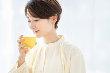 グラスに入った飲み物を飲んでいるミドル世代の女性。