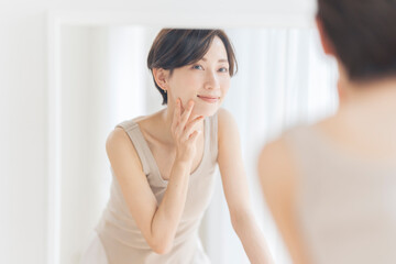 鏡を見ながら頬を触っている女性。