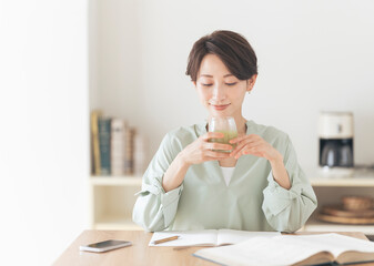 グラスに入った飲み物を飲むミドル世代の女性。