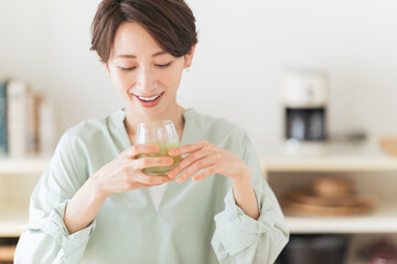 グラスに入った飲み物を飲むミドル世代の女性。