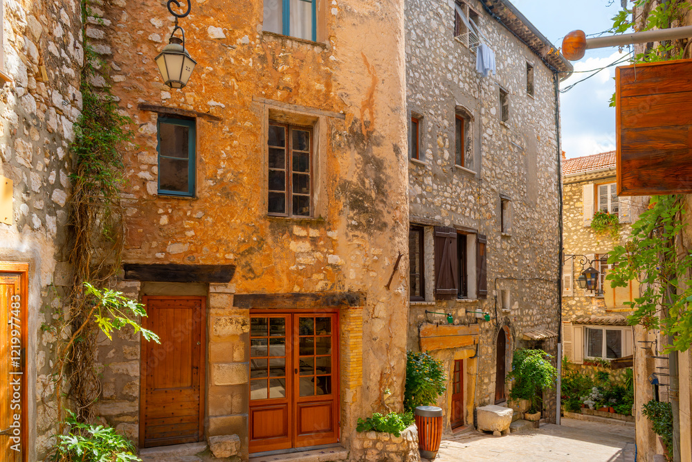 Wall mural A cobblestone alley of shops and apartments in the medieval old town center of the Provence hill town of Tourrettes-sur-Loup, France.