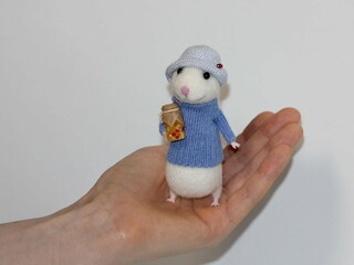 The doll is handmade. Puppet art. In hand is a mouse made of wool.