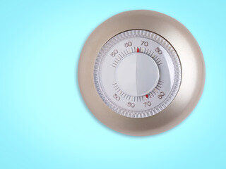 Round thermostat dial on a blue background adjusting temperature settings