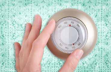 Close-up of a Hand Adjusting a Thermostat Dial With a Lace Background