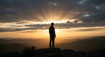 Man standing on top of cliff at sunset