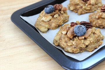Homemade oat and banana cookie topping with blueberry, walnut and pecan on the oven tray, dessert for vegan
