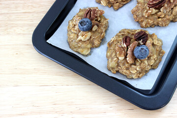 Homemade oat and banana cookie topping with blueberry, walnut and pecan on the oven tray, dessert for vegan