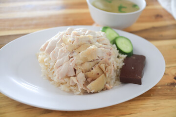 Chicken rice in a white plate with cucumber and soup in a cup, Thai called Khao Man Kai, a famous Thai Food.