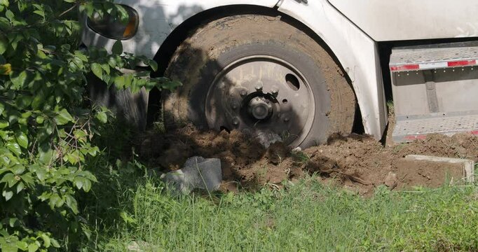 Close-up of truck front wheel stuck in mud in country road. Road conditions after rain. 