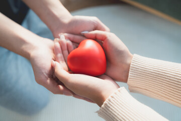 Closeup view of red heart on woman and man hands. Healthy and valentines day concept