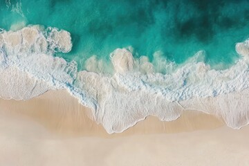 Aerial view of ocean waves breaking on a white sand beach, the turquoise and emerald water creating a vivid contrast with the sand. The waves form delicate foam patterns on the shore.