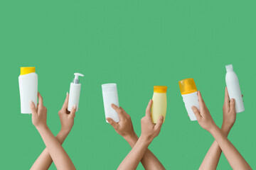 Female hands with bottles of sunscreen cream on green background