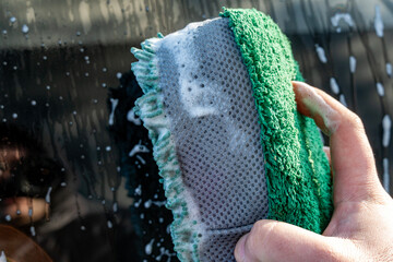 Close-up of a microfiber sponge in operation, washing the car