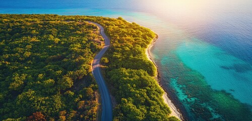 An overhead drone view of a winding coastal road, capturing the lush vegetation and vibrant colors of the ocean, as the sunlight reflects on the water, creating a serene and inviting atmosphere.