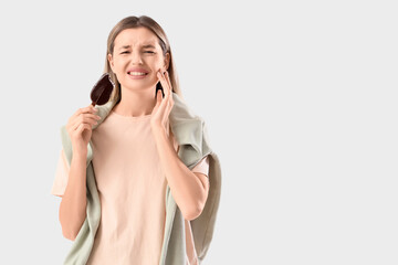 Young woman with cold ice cream suffering from tooth ache on white background