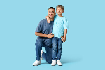 Happy father hugging his little son on blue background