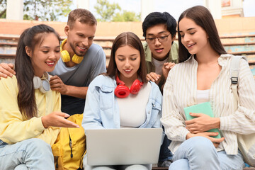 Group of students studying with laptop on benches outdoors