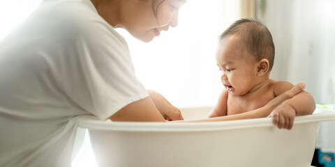 young Asian mother is Bathing with her newborn baby In Bathtub at home.Concept of newborn,baby,parenthood,motherhood,childhood,New life,maternity,love,new family member